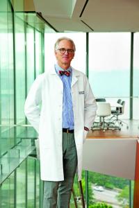 A man in a white coat stands with his hands in his pockets
